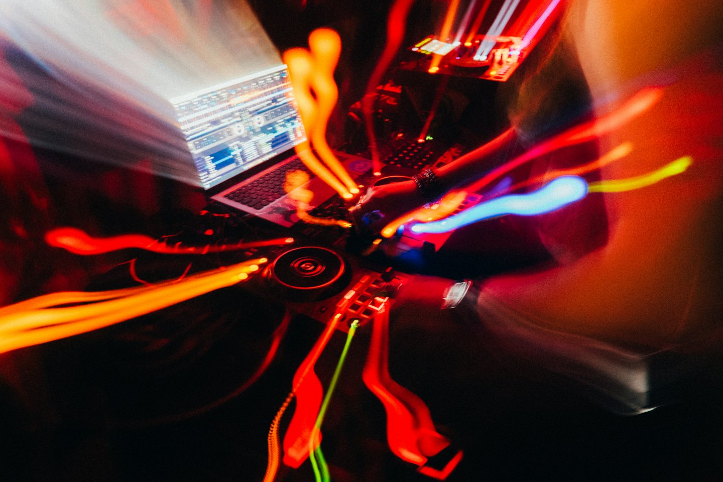 A DJ mixes music on a laptop and soundboard.