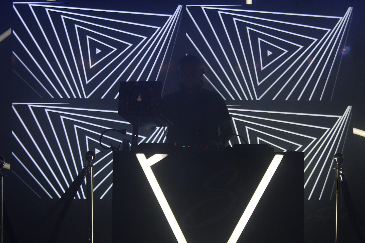 A DJ mixes music behind a glowing booth at an event.