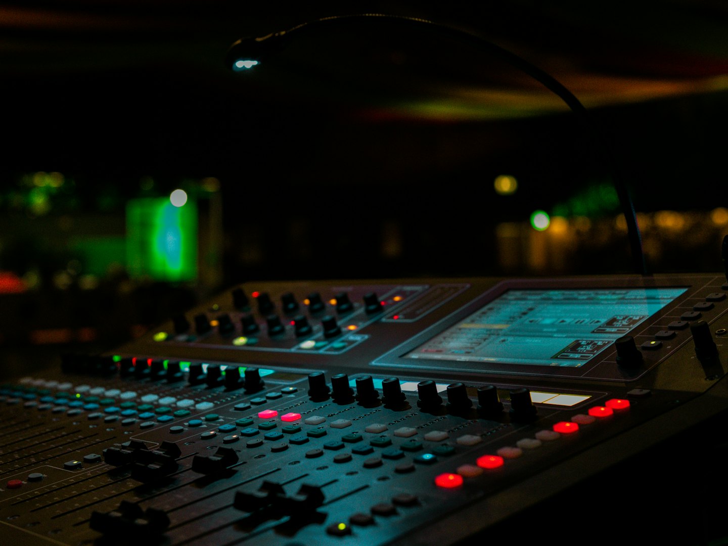Audio mixing console with illuminated buttons and glowing screens.